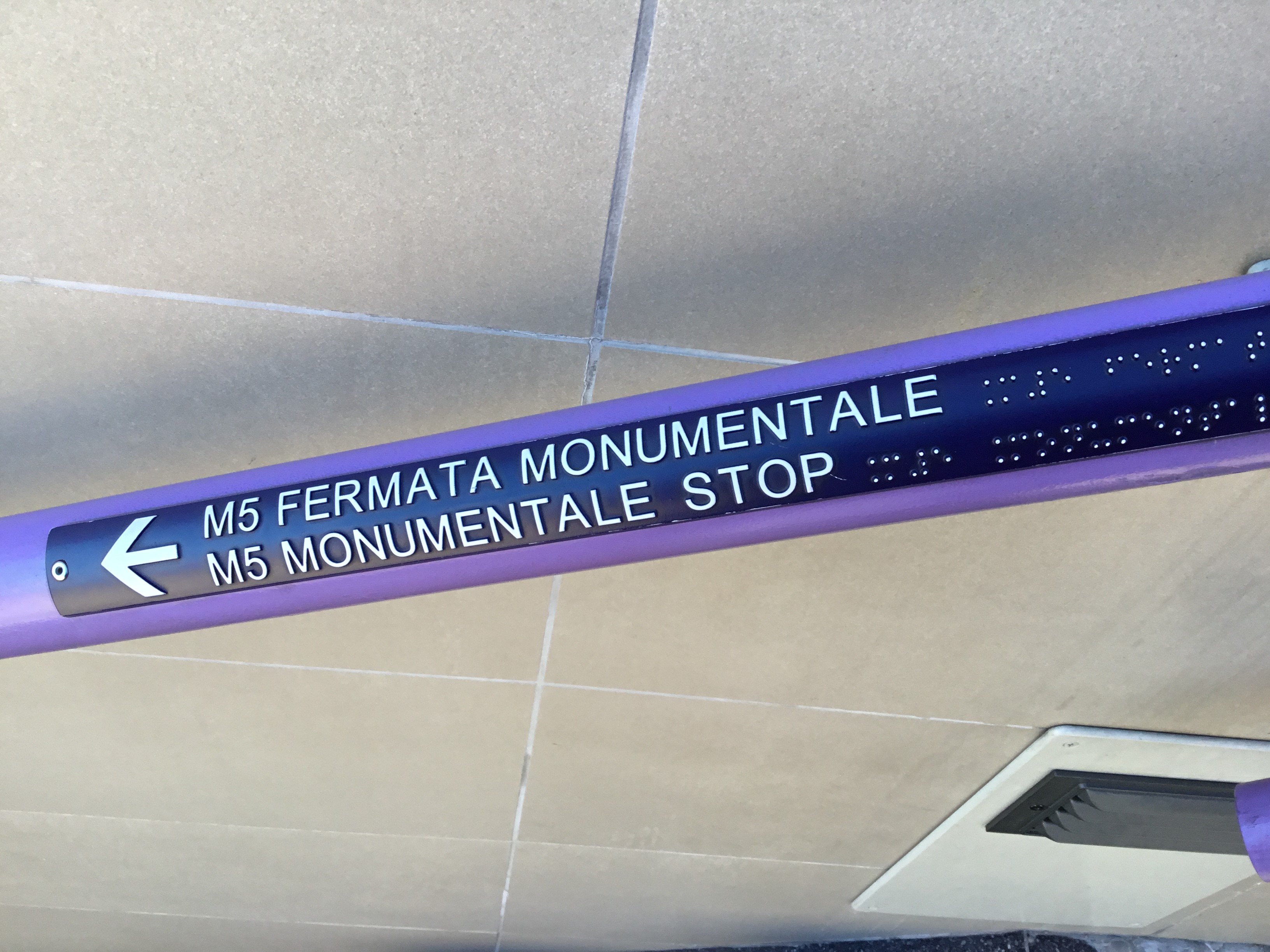 [Milan]Station step handrail showing line colour and directions ti M5 line (with raised text in Italian and English) also in Braille.  Photo by Ian Brown for Railfuture.